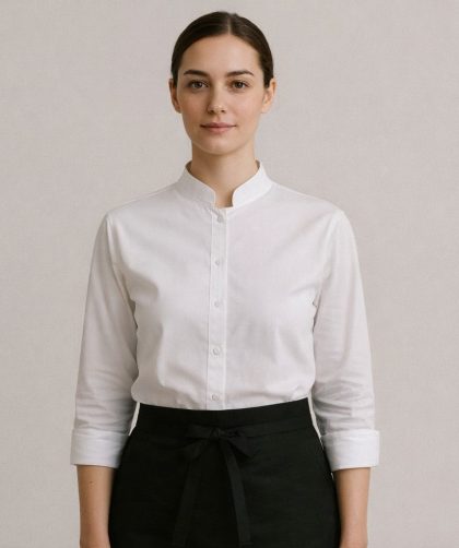 En kvinna i restaurangpersonal i vit skjorta med kinakrage och svart förkläde.