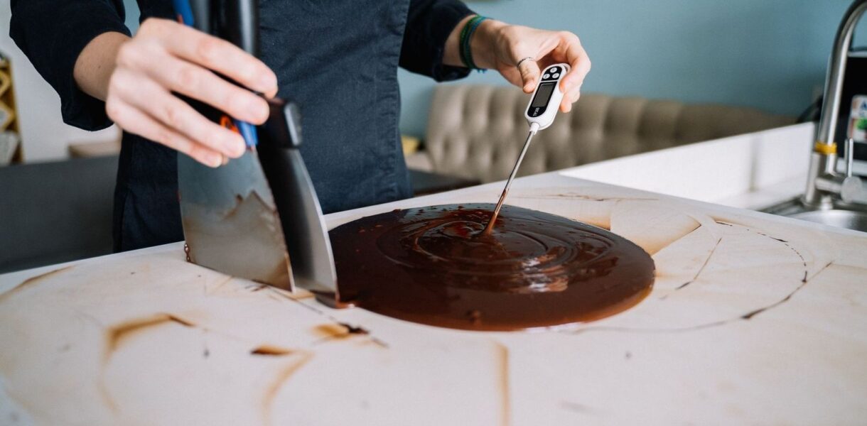 Person mäter temperaturen i smält choklad med digital termometer