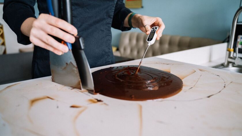 Person mäter temperaturen i smält choklad med digital termometer