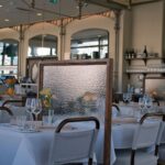 Ljus restaurangmatsal med dukade bord, textilstolar och avskärmande skärmar
