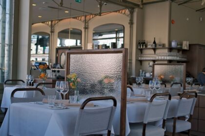 Ljus restaurangmatsal med dukade bord, textilstolar och avskärmande skärmar