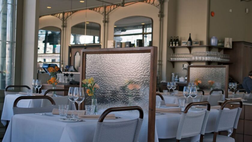 Ljus restaurangmatsal med dukade bord, textilstolar och avskärmande skärmar