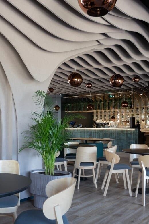Restaurang med vågformade akustikpaneler i taket och många sittplatser