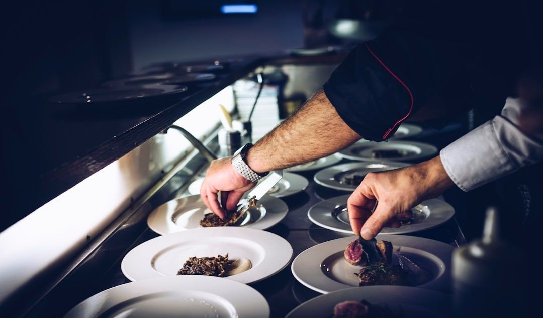Kockar lägger upp mat på tallrikar i ett restaurangkök